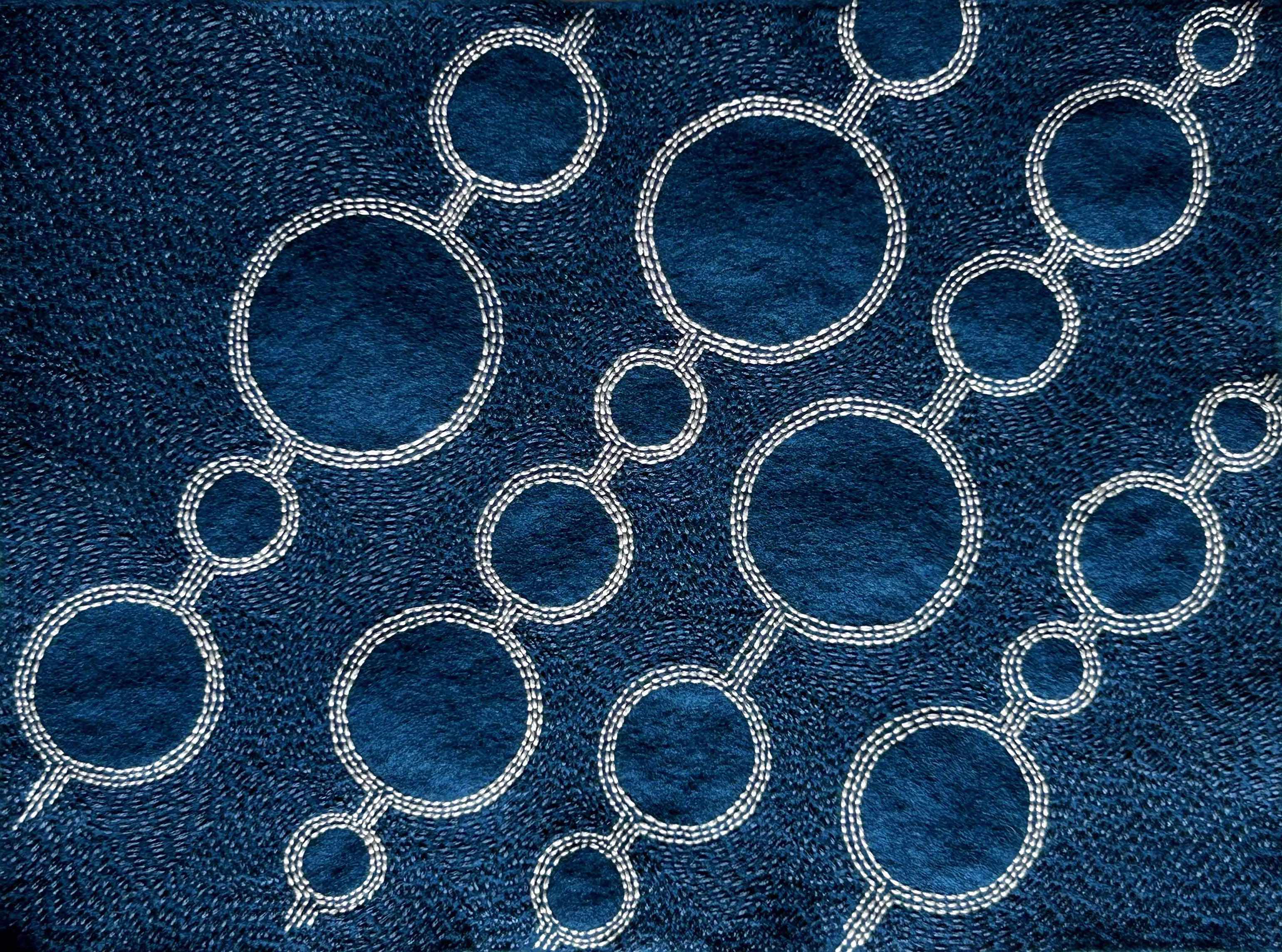 Photo of art white and antique blue thread on teal felt